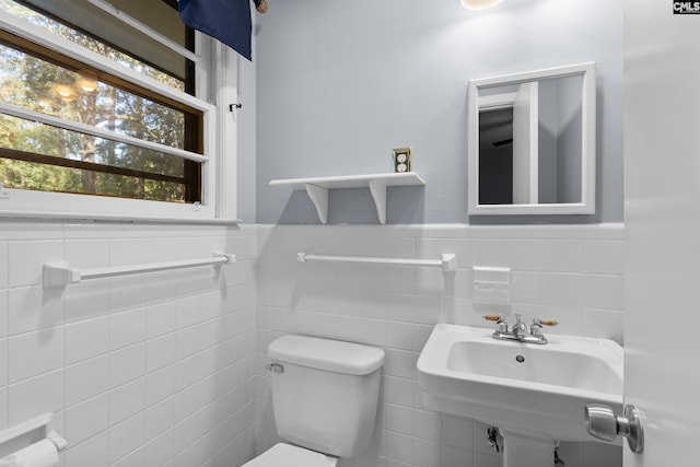 bathroom featuring a wainscoted wall, toilet, and a sink