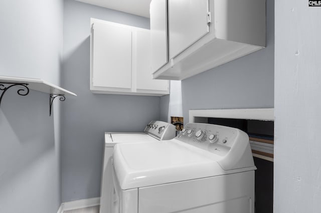 clothes washing area featuring washer and clothes dryer, cabinet space, and baseboards