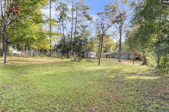 view of yard featuring an outbuilding, a shed, and fence