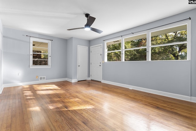 empty room with visible vents, ceiling fan, baseboards, and wood finished floors