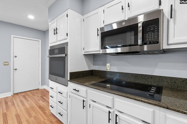 kitchen featuring light wood-type flooring, recessed lighting, dark stone countertops, stainless steel appliances, and white cabinetry