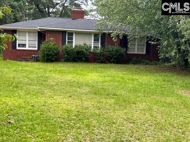 single story home with brick siding, a chimney, and a front yard