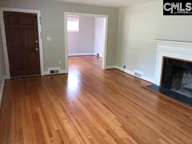 unfurnished living room featuring visible vents, a fireplace, baseboards, and wood finished floors