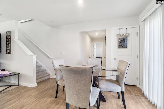 dining area featuring baseboards, stairs, and light wood finished floors