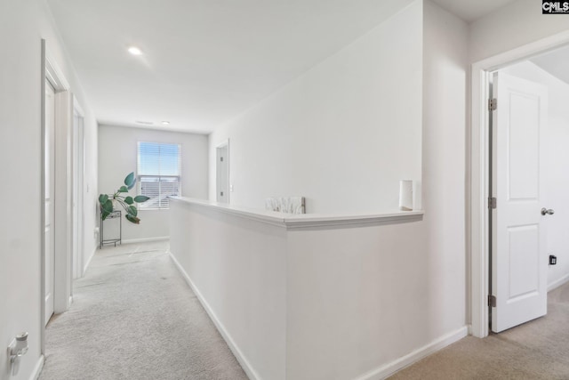 hallway with recessed lighting, light colored carpet, and baseboards