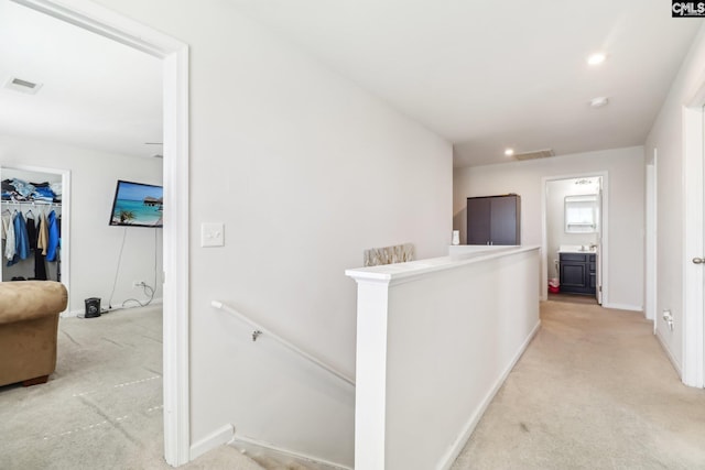 hall with light colored carpet, an upstairs landing, visible vents, and baseboards