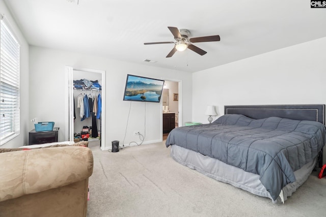 carpeted bedroom featuring a closet, visible vents, multiple windows, and a walk in closet