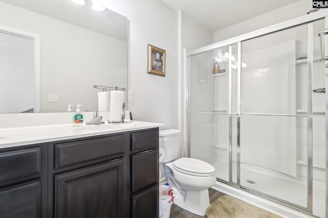 bathroom featuring double vanity, toilet, a stall shower, and a sink