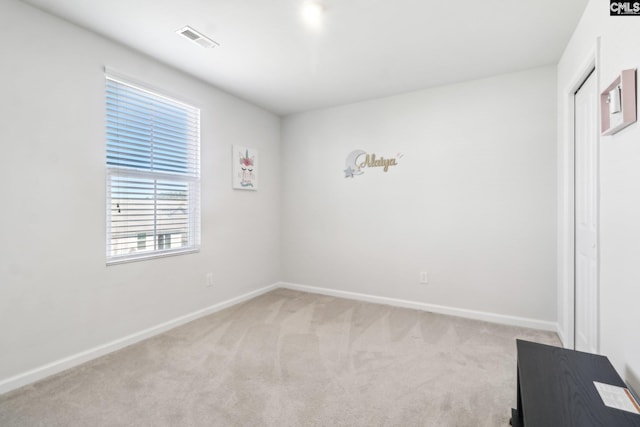 spare room with baseboards, visible vents, and light carpet