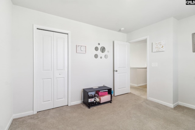 bedroom with a closet, baseboards, and light colored carpet