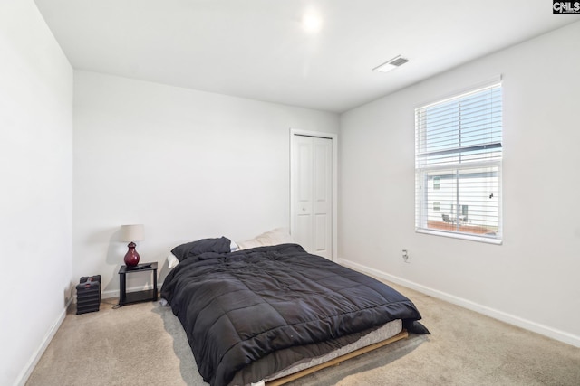 bedroom featuring visible vents, baseboards, light colored carpet, and a closet