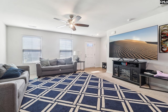 carpeted living room featuring visible vents, baseboards, and a ceiling fan