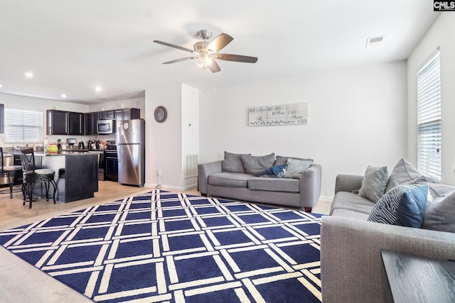 living area with plenty of natural light, visible vents, and ceiling fan