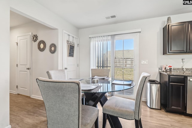 dining area featuring visible vents, baseboards, indoor bar, and light wood-style flooring