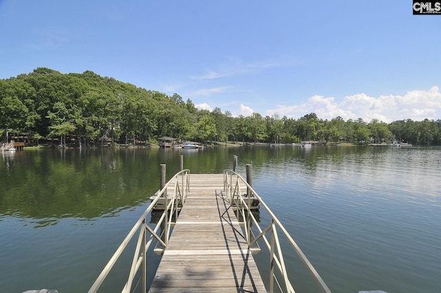 view of dock featuring a wooded view and a water view