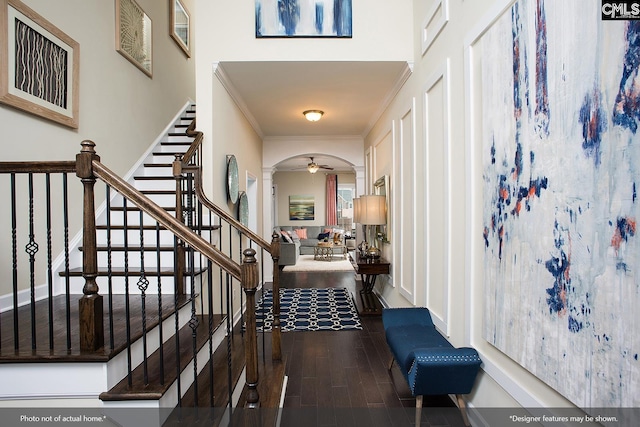 entryway with stairs, arched walkways, wood finished floors, and crown molding