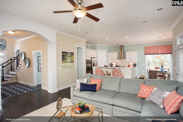 living room featuring dark wood-style floors, a ceiling fan, visible vents, arched walkways, and ornamental molding