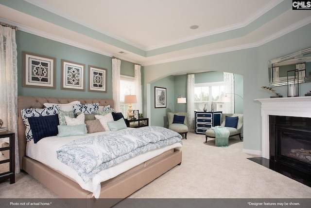 bedroom featuring arched walkways, a fireplace with flush hearth, crown molding, and carpet floors