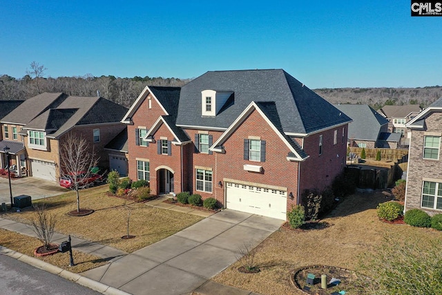 traditional home featuring a residential view, concrete driveway, an attached garage, a front yard, and brick siding