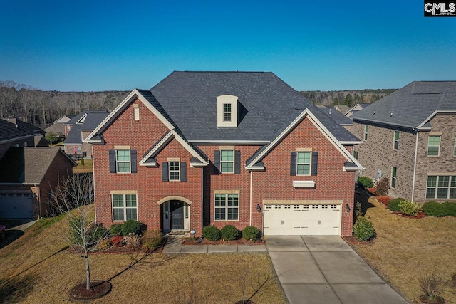 view of front facade with a front yard, driveway, roof with shingles, a garage, and brick siding