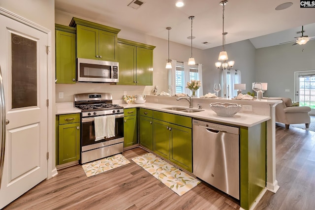 kitchen with visible vents, a sink, stainless steel appliances, a peninsula, and green cabinetry