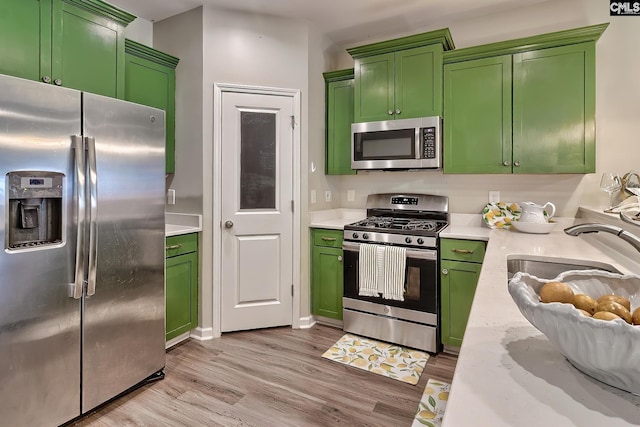 kitchen featuring green cabinetry, stainless steel appliances, light wood-type flooring, and light stone counters