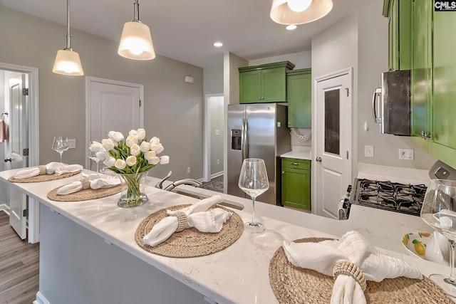 kitchen with light wood-type flooring, decorative light fixtures, recessed lighting, appliances with stainless steel finishes, and green cabinetry