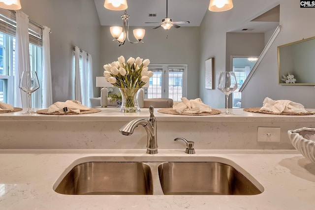 details with light stone counters, visible vents, ceiling fan, and a sink