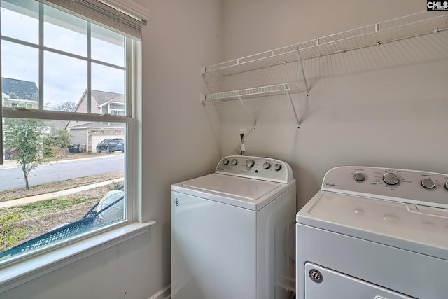 clothes washing area with laundry area, a healthy amount of sunlight, and separate washer and dryer