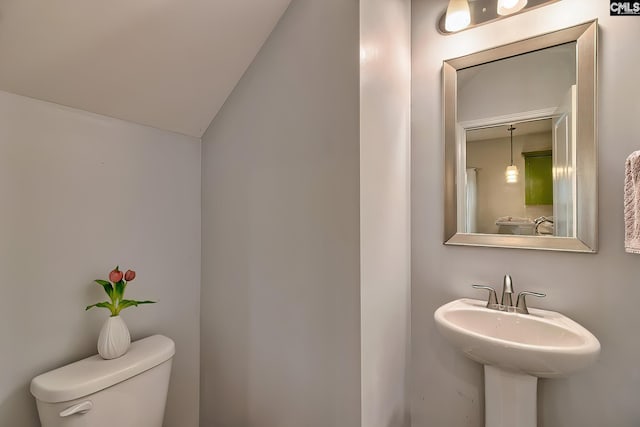 bathroom with vaulted ceiling, toilet, and a sink