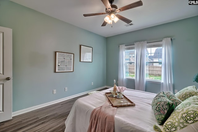 bedroom with visible vents, baseboards, dark wood finished floors, and a ceiling fan