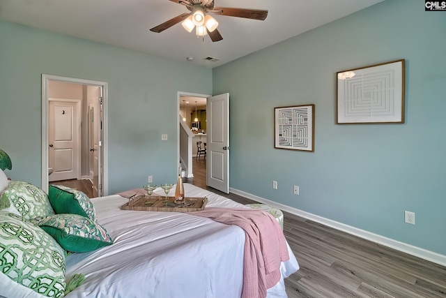 bedroom featuring visible vents, ensuite bathroom, wood finished floors, baseboards, and ceiling fan