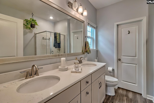 full bathroom featuring wood finished floors, a shower stall, toilet, and a sink