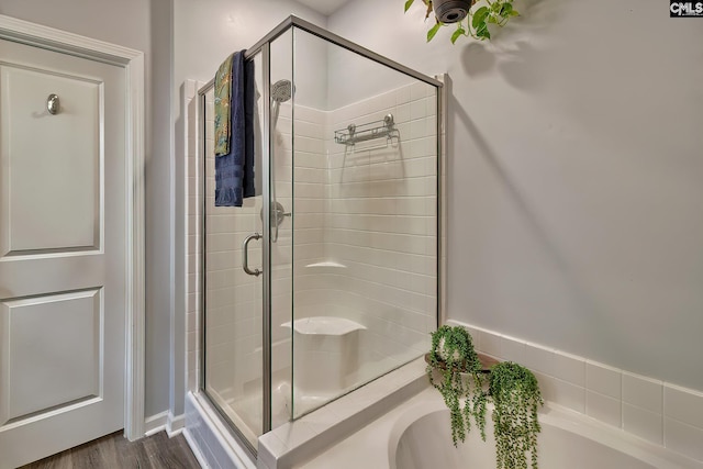 full bathroom with a shower stall, a garden tub, and wood finished floors