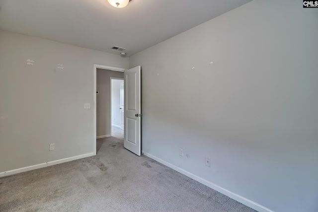 spare room with visible vents, light colored carpet, and baseboards