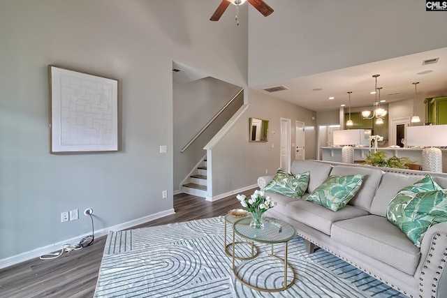 living area featuring visible vents, wood finished floors, a ceiling fan, and stairway