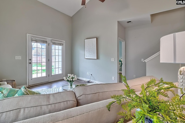 living area featuring wood finished floors, baseboards, visible vents, lofted ceiling, and ceiling fan