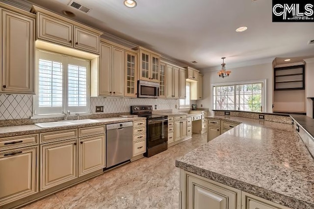 kitchen featuring visible vents, cream cabinets, stainless steel appliances, and a sink