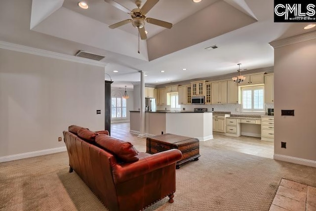 living room with a tray ceiling, visible vents, light carpet, and ornamental molding