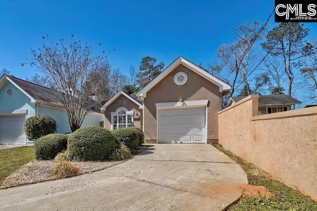 view of front of property with concrete driveway, fence, a garage, and stucco siding