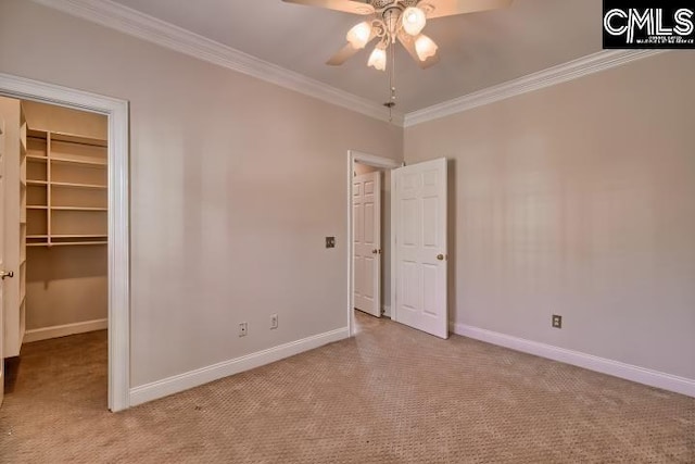 unfurnished bedroom featuring baseboards, a spacious closet, a closet, light carpet, and crown molding