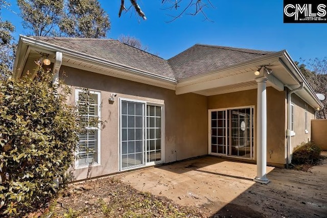 back of property featuring a patio, roof with shingles, and stucco siding