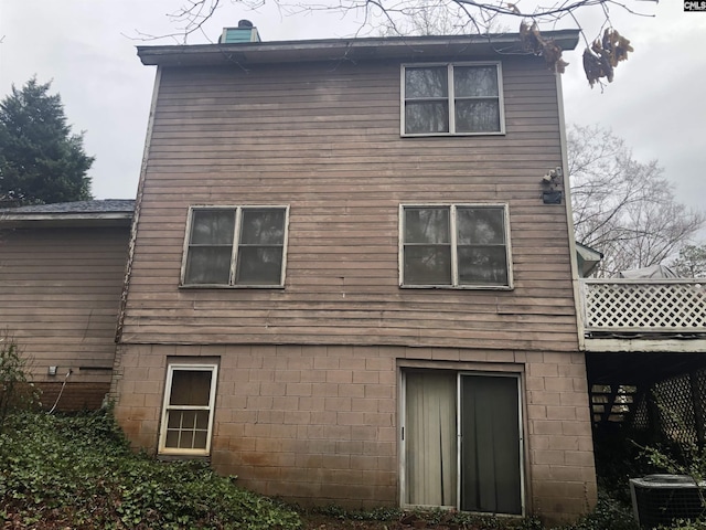 back of house with cooling unit and a chimney