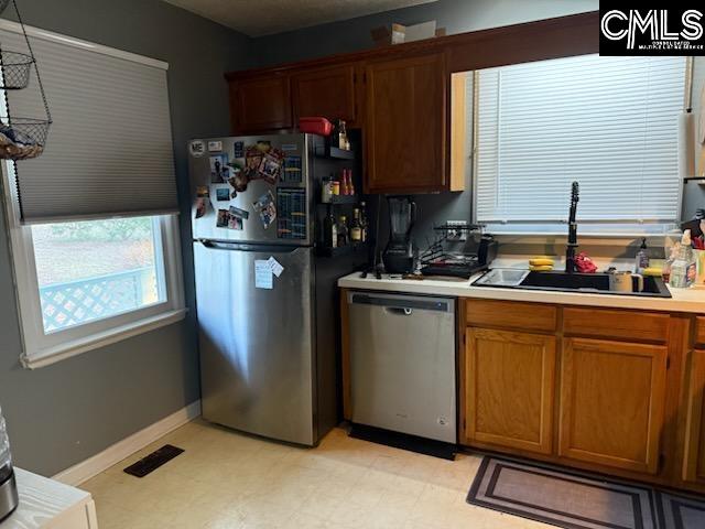 kitchen with visible vents, a sink, appliances with stainless steel finishes, light countertops, and light floors