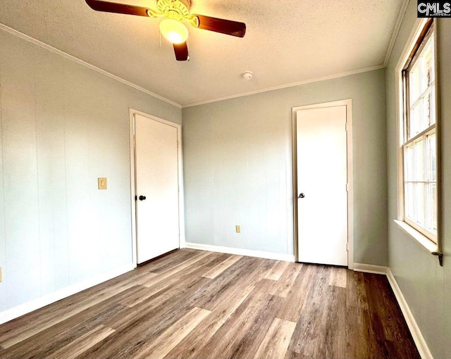 unfurnished bedroom featuring baseboards, a textured ceiling, wood finished floors, and crown molding