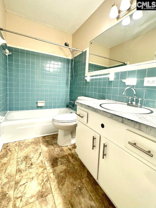 full bath featuring toilet, shower / bathtub combination, a textured ceiling, tile walls, and vanity