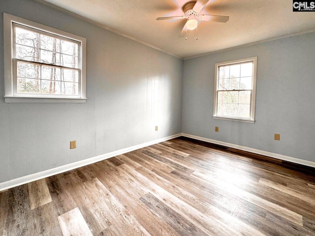 empty room featuring ornamental molding, baseboards, a ceiling fan, and wood finished floors