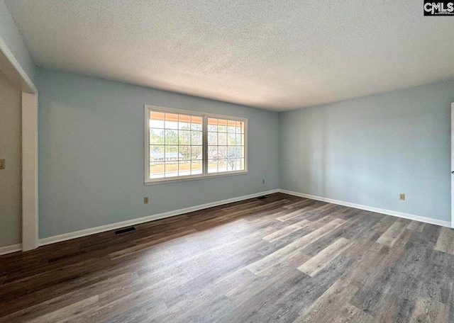 unfurnished room with dark wood-style floors, visible vents, a textured ceiling, and baseboards