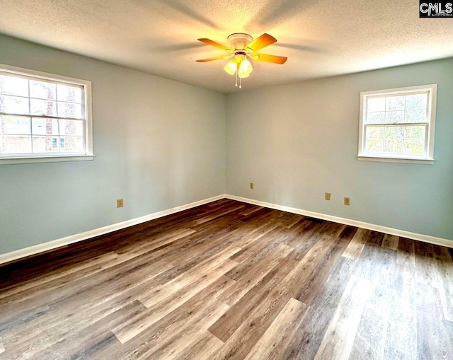 unfurnished room with a wealth of natural light, wood finished floors, a textured ceiling, and ceiling fan