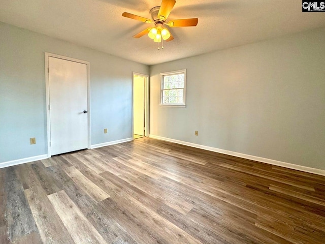 unfurnished bedroom featuring ceiling fan, baseboards, and wood finished floors